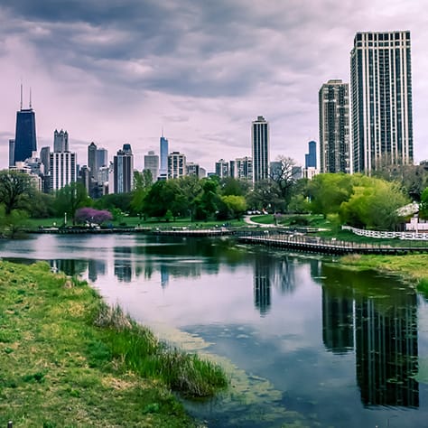 A view of Chicago's skyline from a park with a pond.