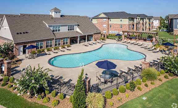 A large swimming pool surrounded by a black fence and a building with a tower on top.