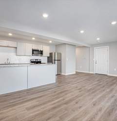 A kitchen with white cabinets and a wooden floor.at Palisades Apartments, Missouri, 64133