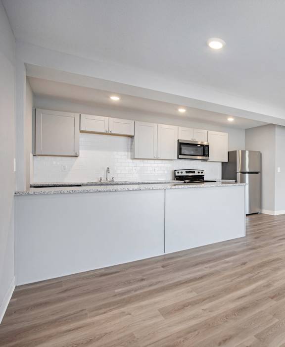 A kitchen with white cabinets and a wooden floor.at Palisades Apartments, Kansas City Missouri