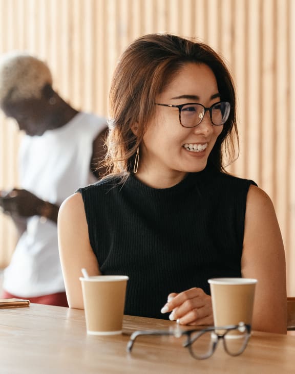a woman sitting at a table with a cup of coffee at The Mera, St Louis Park, MN 55426