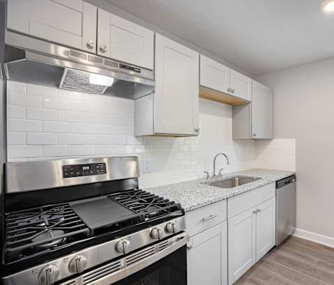 A kitchen with a stove top oven and white cabinets.at Palisades Apartments, Kansas City, MO