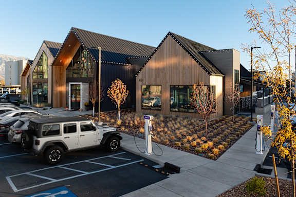 A white SUV is parked in a parking lot in front of a modern building at Solhavn Apartments, Utah