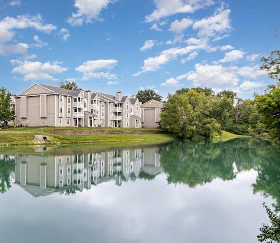 A large building is reflected in the still water of a lake.