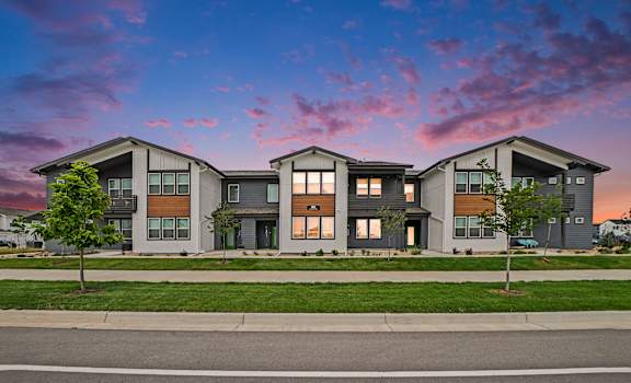 A modern apartment building with a green lawn in front.