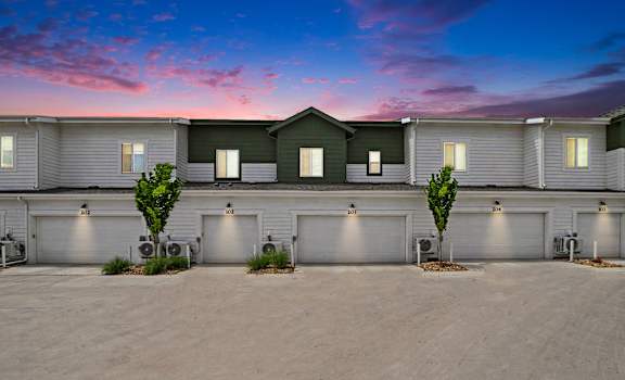 A row of houses with garages and trees in front.