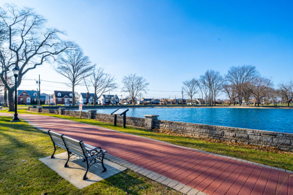 a park bench next to a body of water at The Botanic, Carteret, 07008
