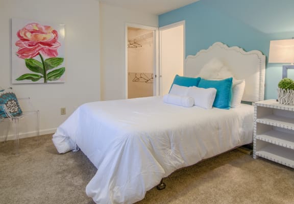 a bedroom with a large white bed with blue pillows and a pink flower on the wall