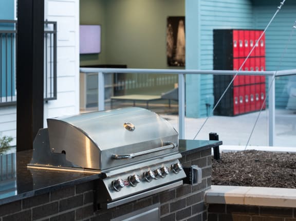a stainless steel barbecue grill on a brick wall in a backyard