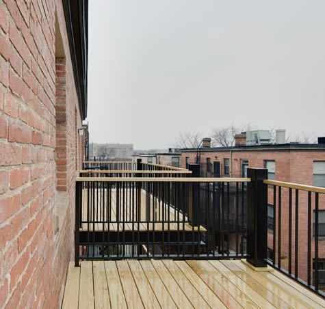 a balcony with a wooden floor and a brick wall