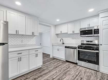 A modern kitchen with white cabinets and stainless steel appliances.