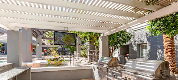 A patio with a grill and a TV on the wall.