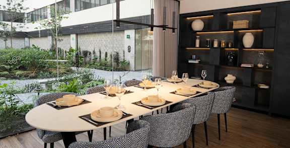 A modern dining room with a long table set for a meal.
