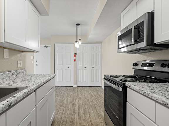 A kitchen with white cabinets and a black stove top oven.