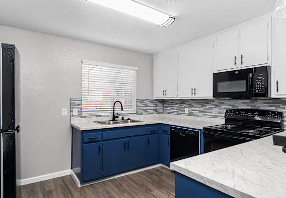 A kitchen with blue cabinets and a black refrigerator.