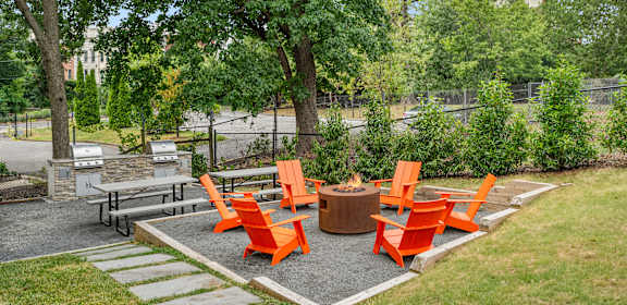 a group of orange chairs around a fire pit in a park
