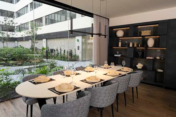 A modern dining room with a long table set for a meal.