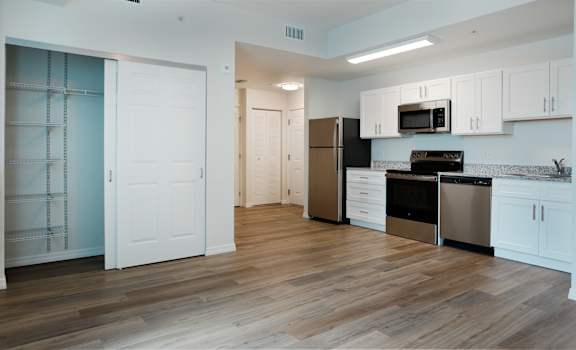 A kitchen with white cabinets and a black fridge.