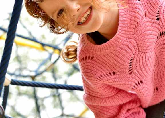 A young boy is playing on a slide at a playground.