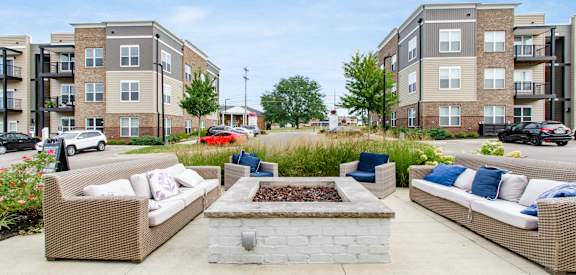 an outdoor patio with couches and a fire pit in front of an apartment building