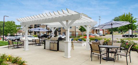 an outdoor patio with tables and chairs and a white pergola
