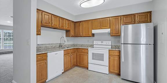 an empty kitchen with wooden cabinets and stainless steel appliances
