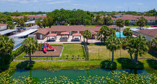 an aerial view of a park with a playground and a pond