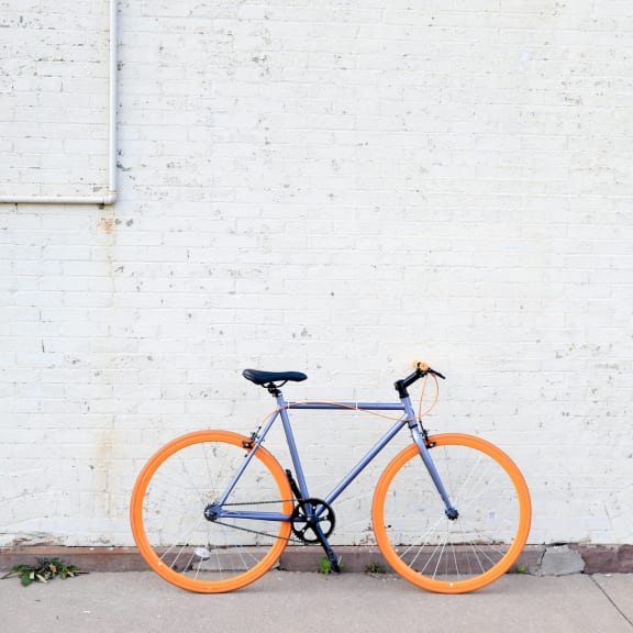 an orange and blue bike parked next to a white brick wall