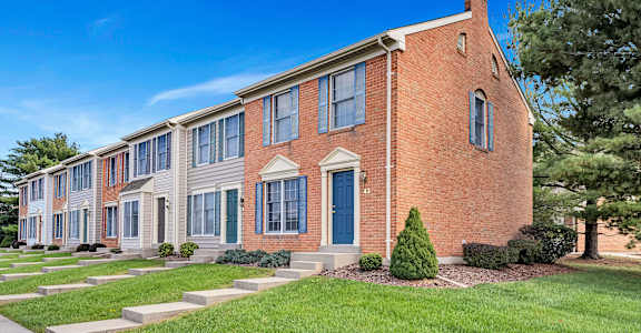 a brick building with blue doors and grass and trees