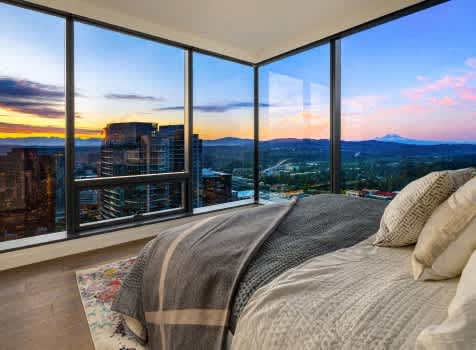 the master bedroom has a view of the city skyline and the mountains in the distance at Two Lincoln Tower Apartments, Bellevue, WA, 98004