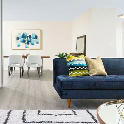 a living room with a blue couch and a table and chairs