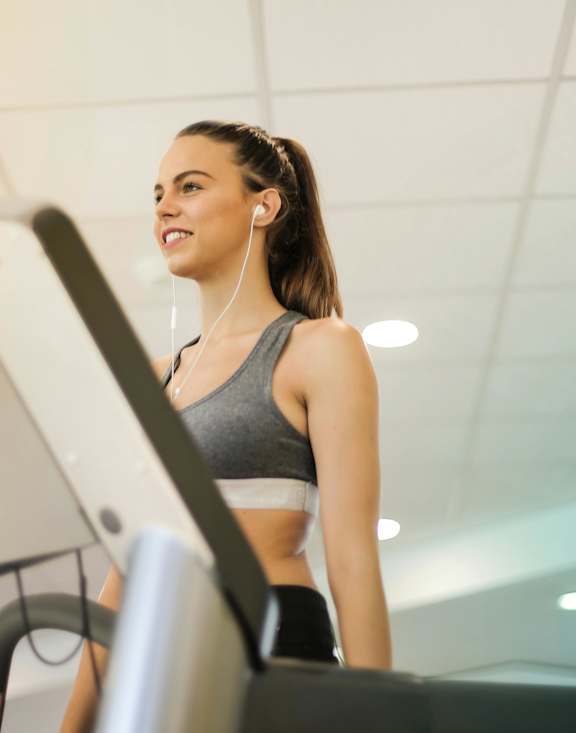 A woman is running on a treadmill in a gym.