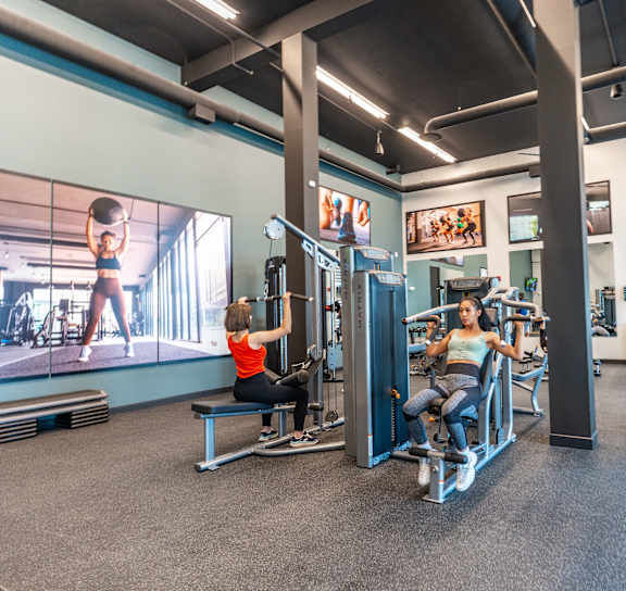 A man and a woman are working out in a gym.