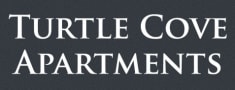 a white turtle cove apartments sign on a black wall