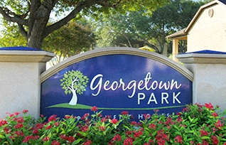 A sign for Georgetown Park is surrounded by flowers.