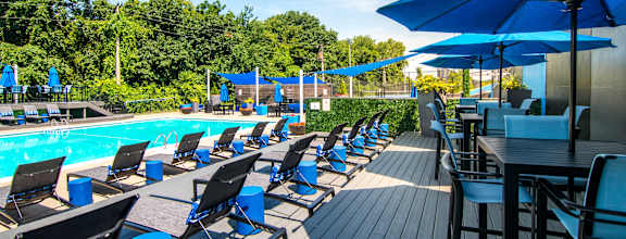 A poolside area with blue umbrellas and chairs.