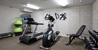 A gym room with a treadmill, exercise bike, and weights.