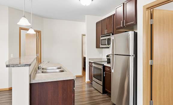 A kitchen with a refrigerator, sink, and cabinets.