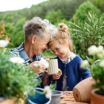 A little girl and an older woman sitting at a table in a garden