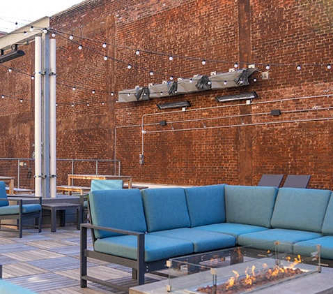 a seating area with blue couches and chairs around a fire pit at East 4th Street, Cleveland, OH