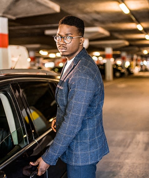 a man standing next to a car in a parking garage at East 4th Street, Cleveland, OH