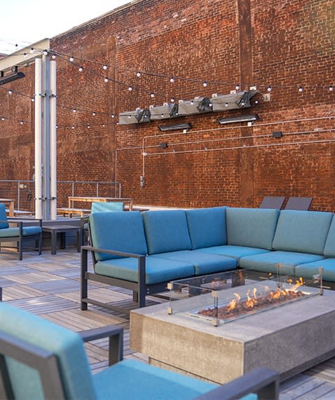 a seating area with blue couches and chairs around a fire pit at East 4th Street, Cleveland, OH, 44115