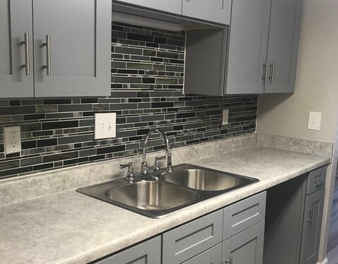 a kitchen with a stainless steel sink and white cabinets
