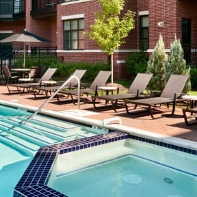 a swimming pool with chaise lounge chairs in front of a brick building at The Sheffield Englewood, Englewood, NJ
