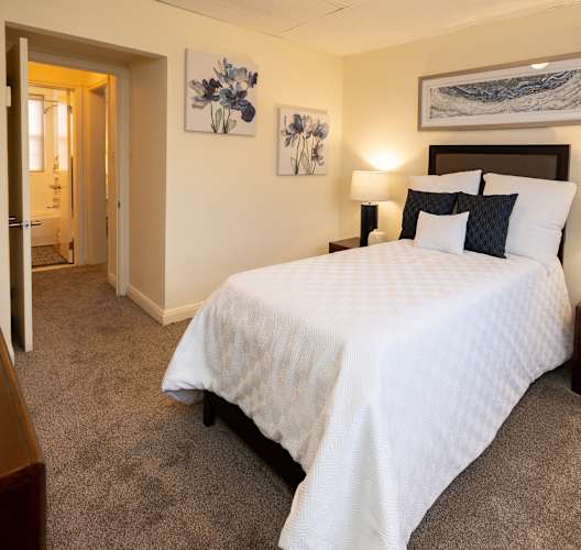 A bedroom with a large bed and two lamps.