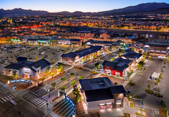 a city at night with lights on and mountains in the background