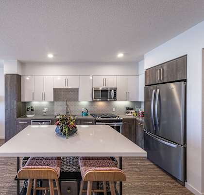 a kitchen with stainless steel appliances and a white island with four chairs
