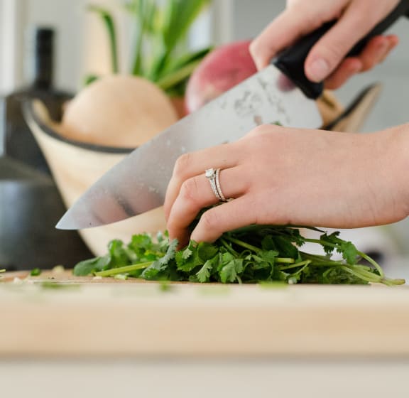 Woman's hand hutting herbs on kitchen counter