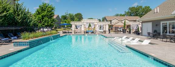 A large swimming pool with a blue tiled edge and a white fence around it.
