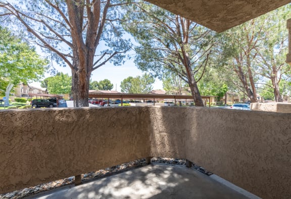 a balcony with a view of trees and a parking lot